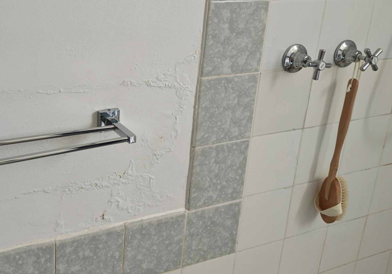 Bathroom wall with bubbling plaster and pipe leaks